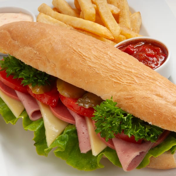 A large Jean's Cafe submarine sandwich with fries, ketchup, and a creamy dipping sauce.