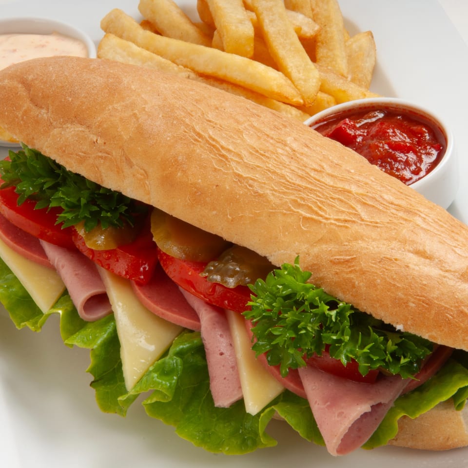 A large Jean's Cafe submarine sandwich with fries, ketchup, and a creamy dipping sauce.